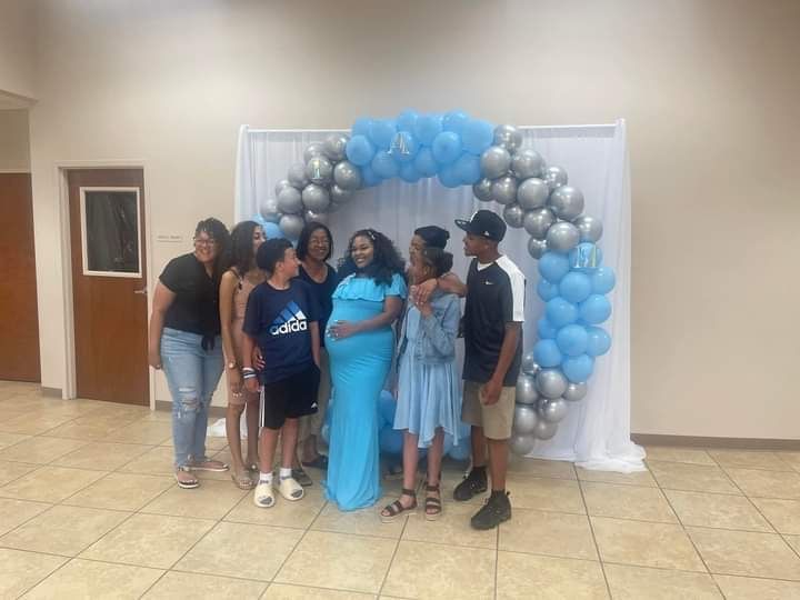 A group of people are posing for a picture in front of a balloon arch.