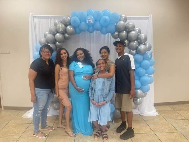 A group of people are posing for a picture in front of a balloon arch.