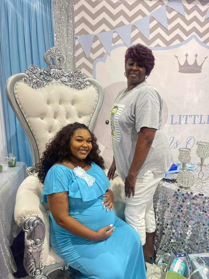 A pregnant woman is sitting in a chair next to another woman.