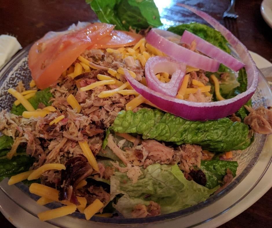 A salad with tuna , lettuce , cheese and onions on a plate