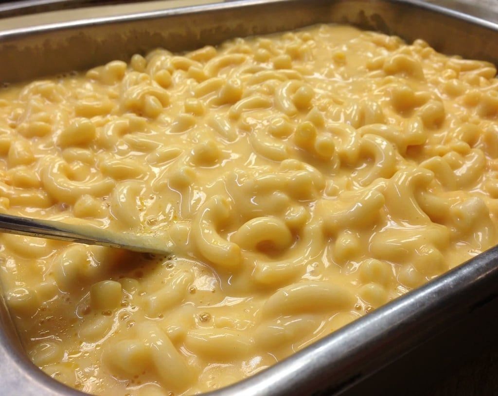 A tray of macaroni and cheese with a spoon in it.