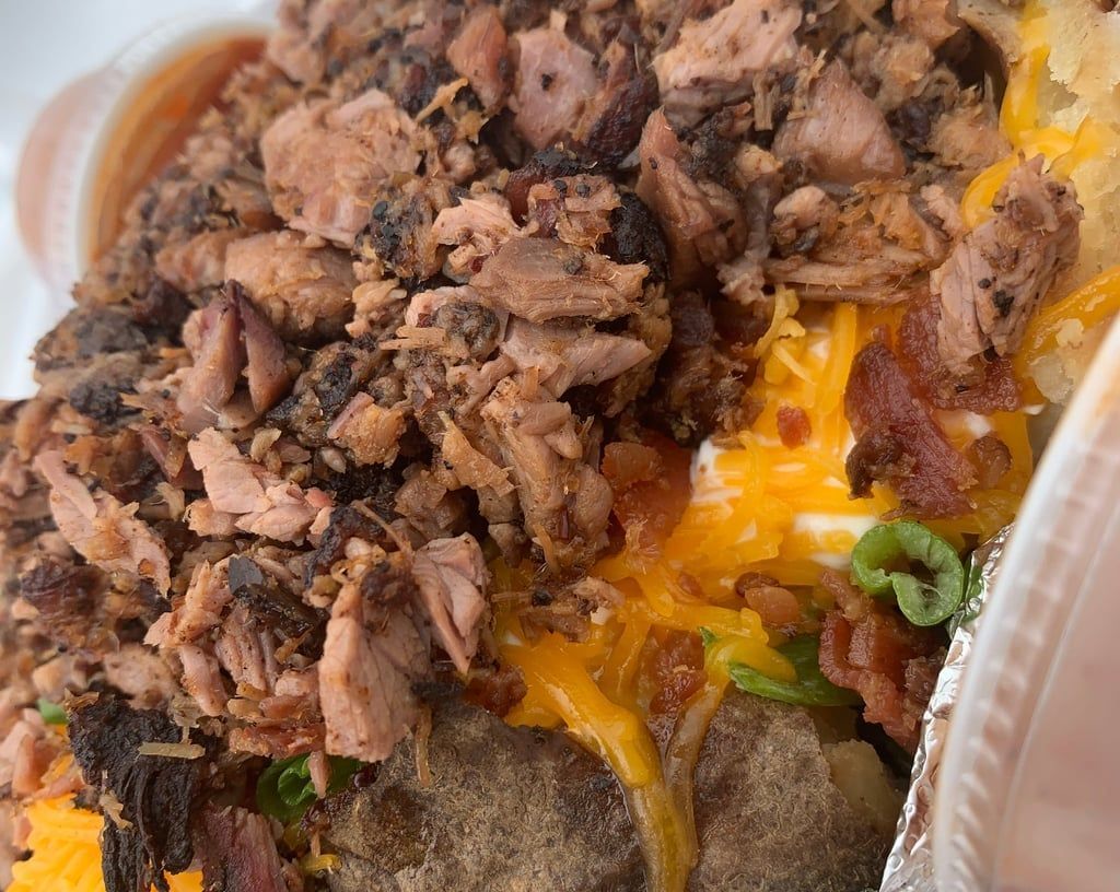 A close up of a plate of food with meat , cheese , and bacon.