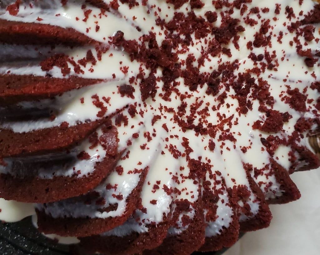 A red velvet cake with white frosting and red sprinkles