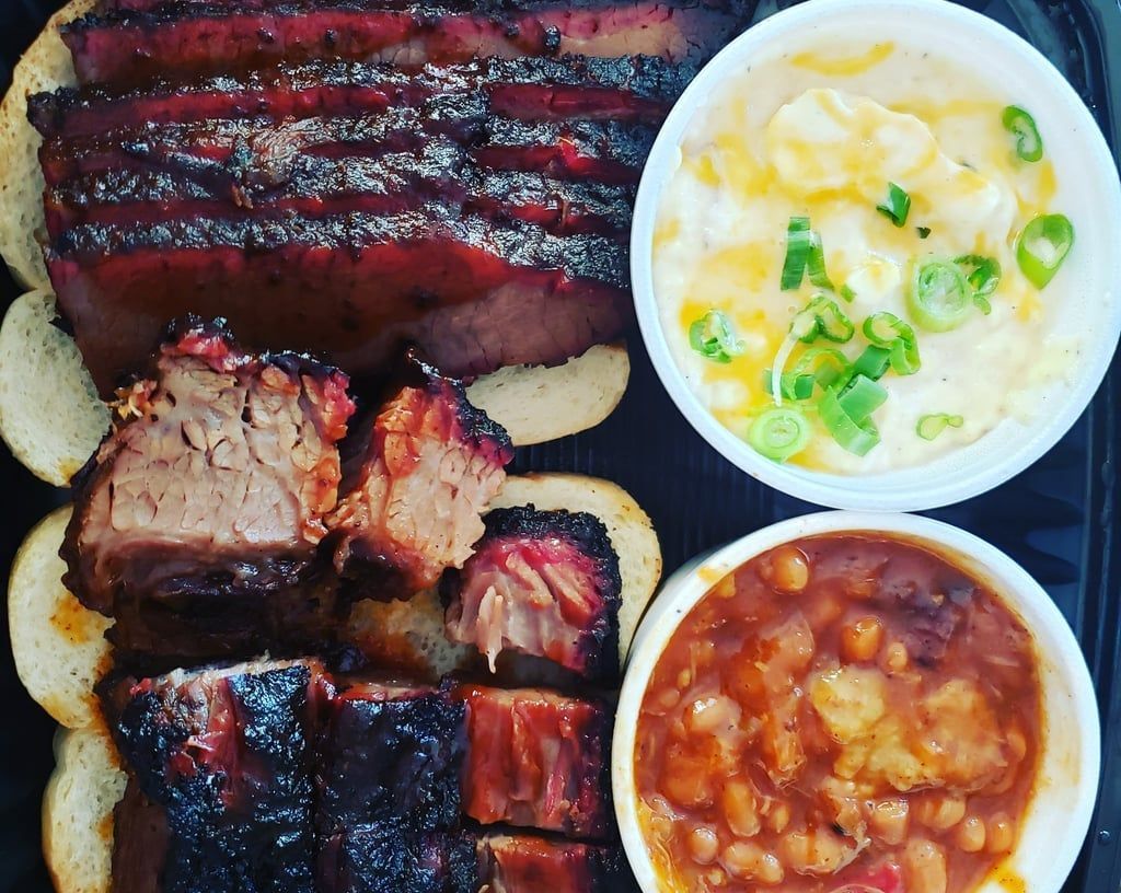 A plate of food with meat , beans , macaroni and cheese , and green onions.