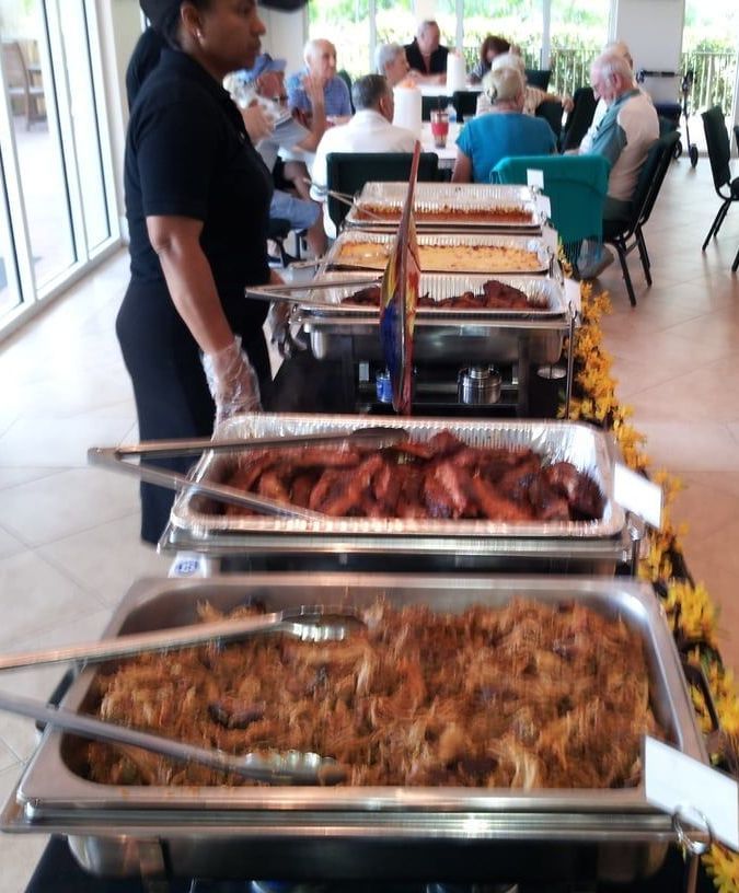 A woman stands behind a buffet line full of food