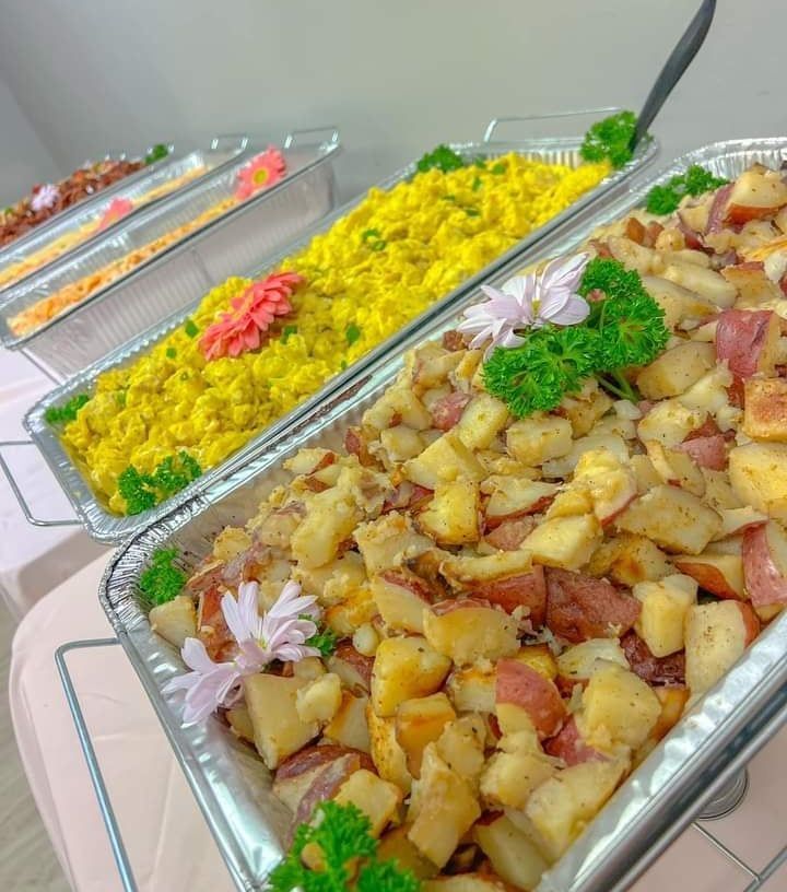 Several trays of food on a table including rice and potatoes