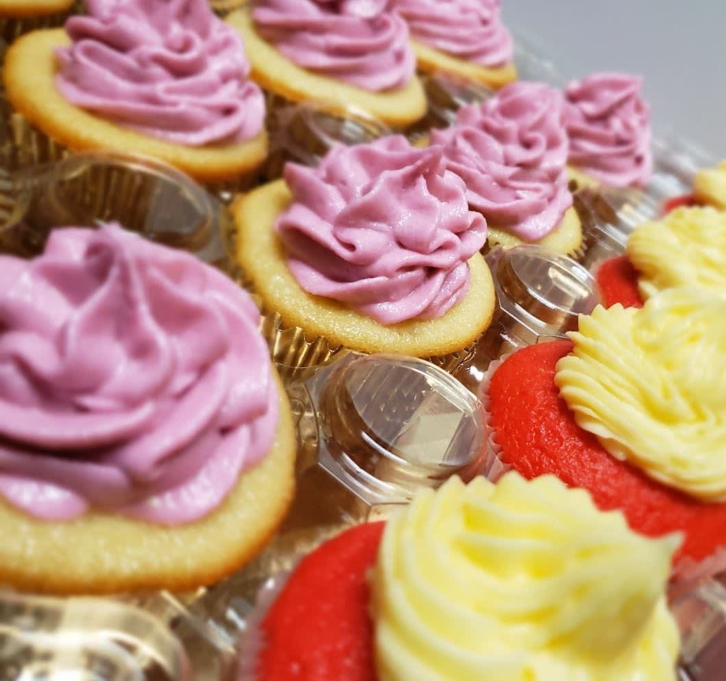 A bunch of cupcakes with pink and yellow frosting