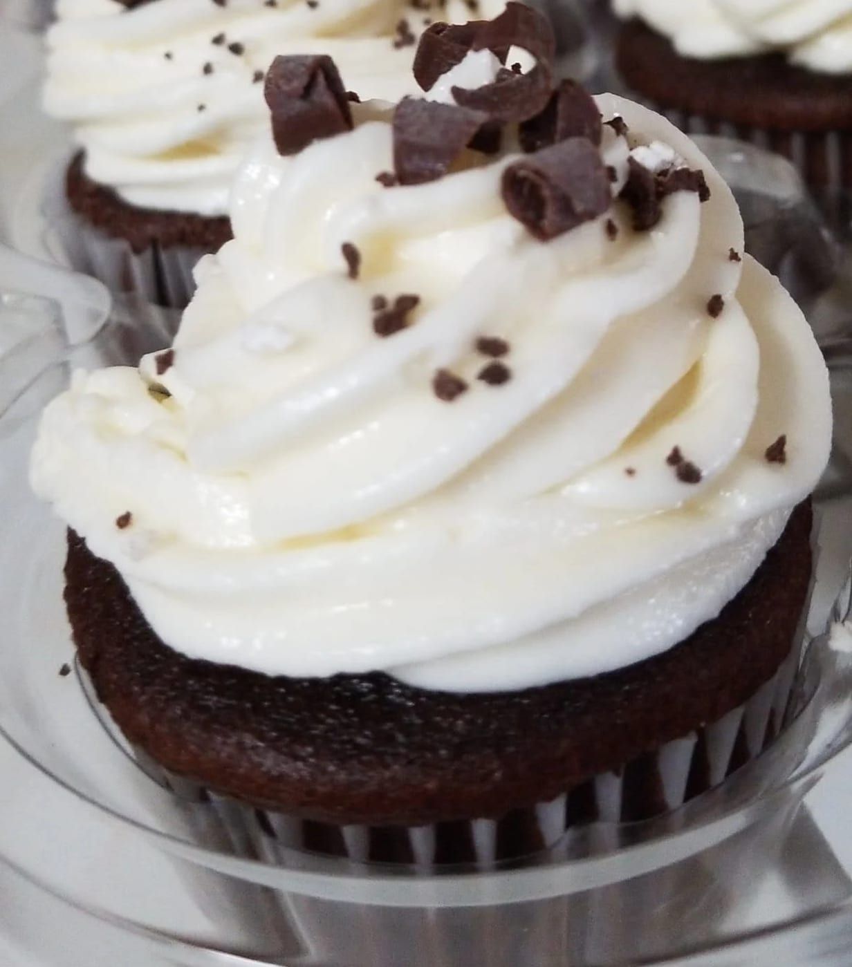 A chocolate cupcake with white frosting and chocolate shavings on top