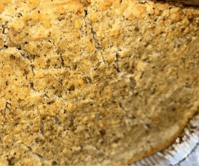 A close up of a piece of bread with crumbs on it.