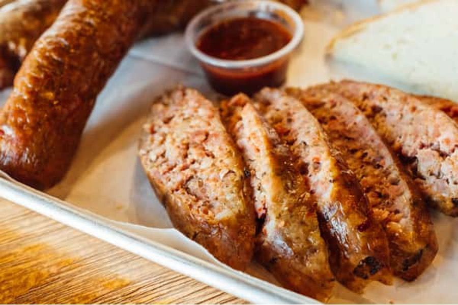 A close up of a plate of sausage and meatloaf on a table.