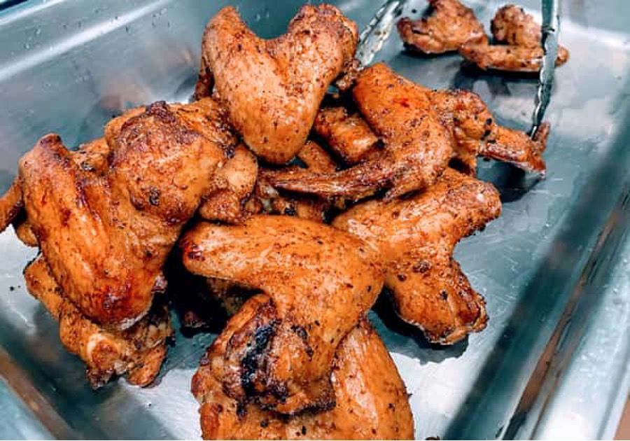 A tray of chicken wings with tongs in it