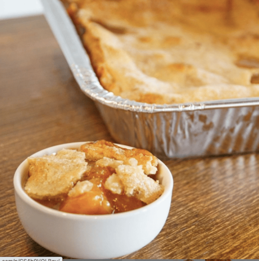 A bowl of peach cobbler next to a pan of pie