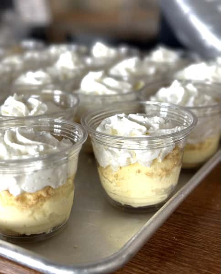 A tray of dessert cups with whipped cream on top