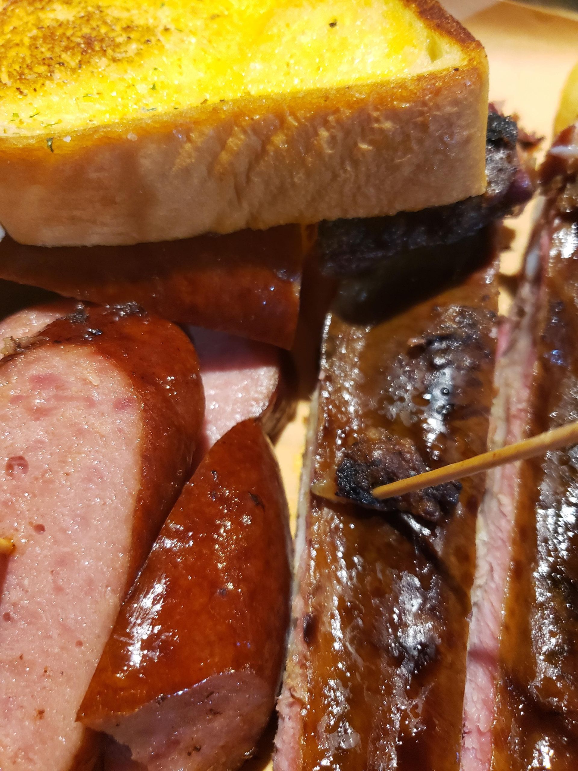 A close up of meat and bread with a toothpick in itnk