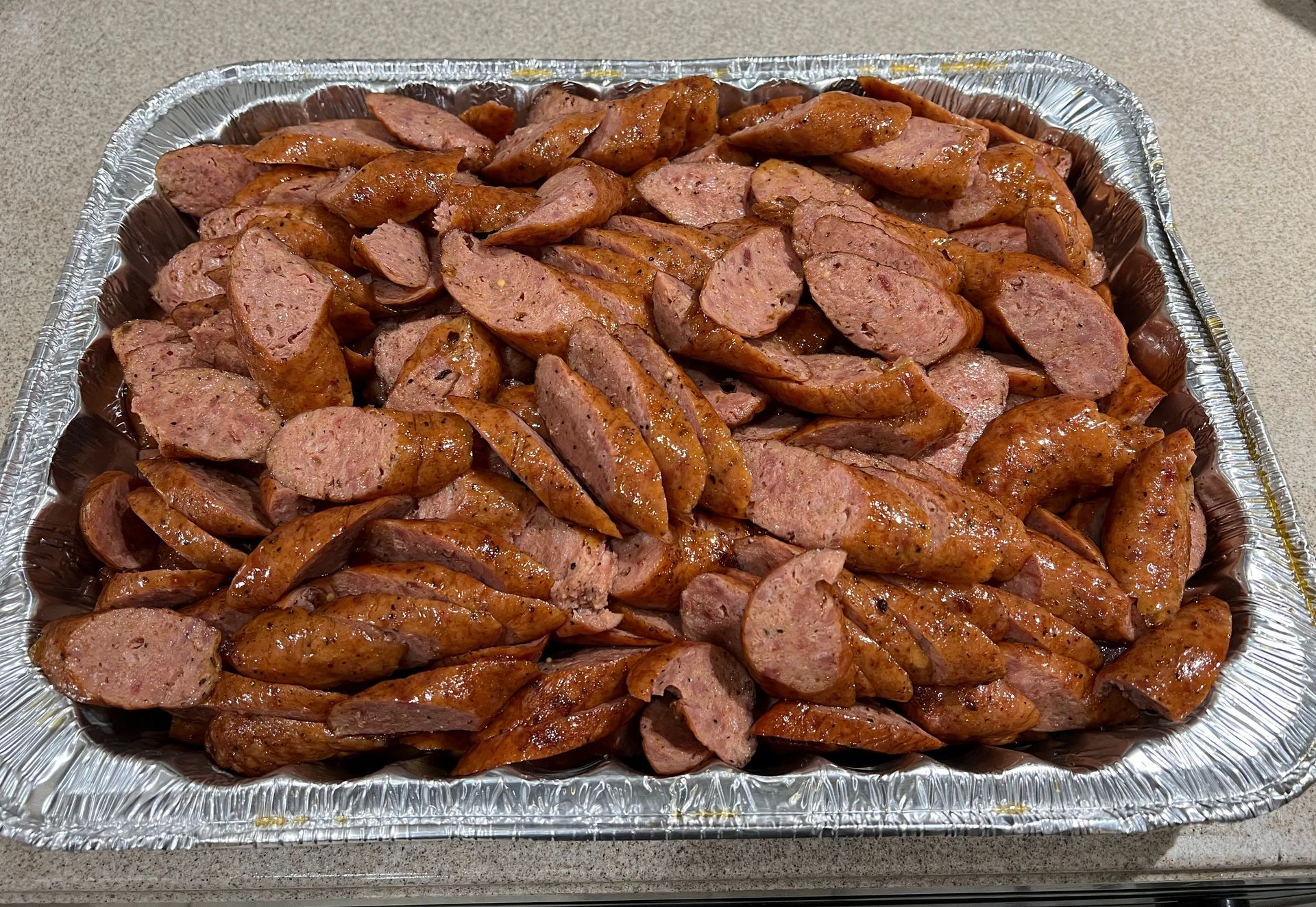 A tray of sausage is sitting on a counter.