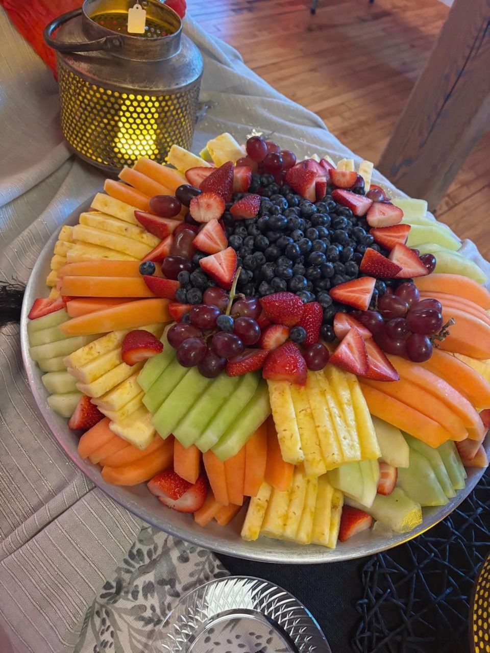 A plate of fruit is sitting on a table next to a candle holder.
