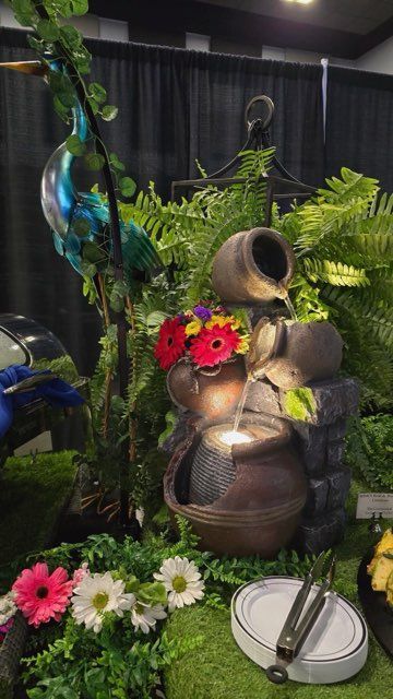 A water fountain surrounded by flowers and plants in a garden.