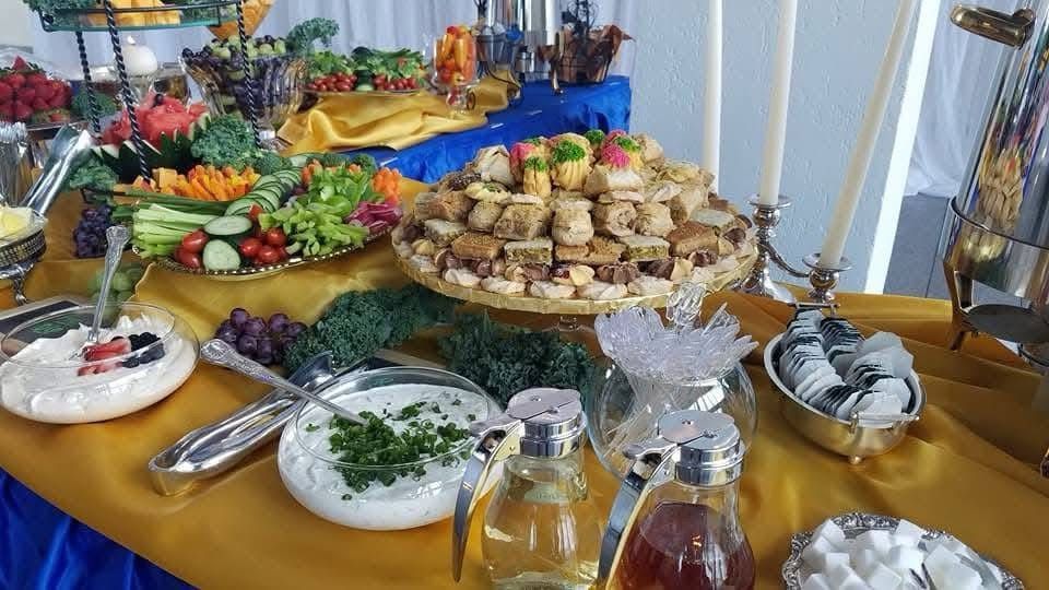 A buffet table with plates of food and candles on it.