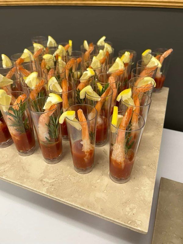 A table topped with glasses filled with shrimp and tomato sauce.