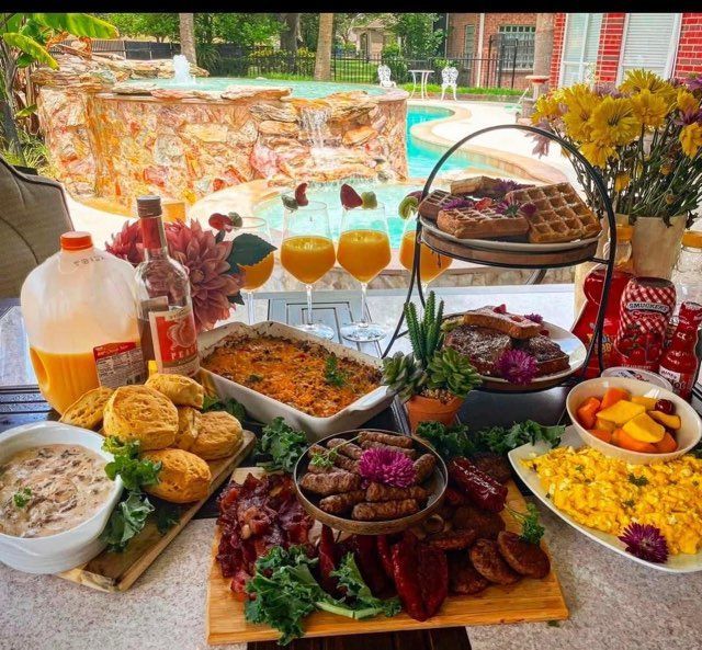 A table full of food and drinks with a pool in the background