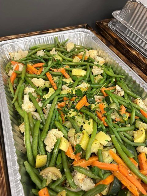 A pan filled with green beans , carrots , cauliflower , and other vegetables.