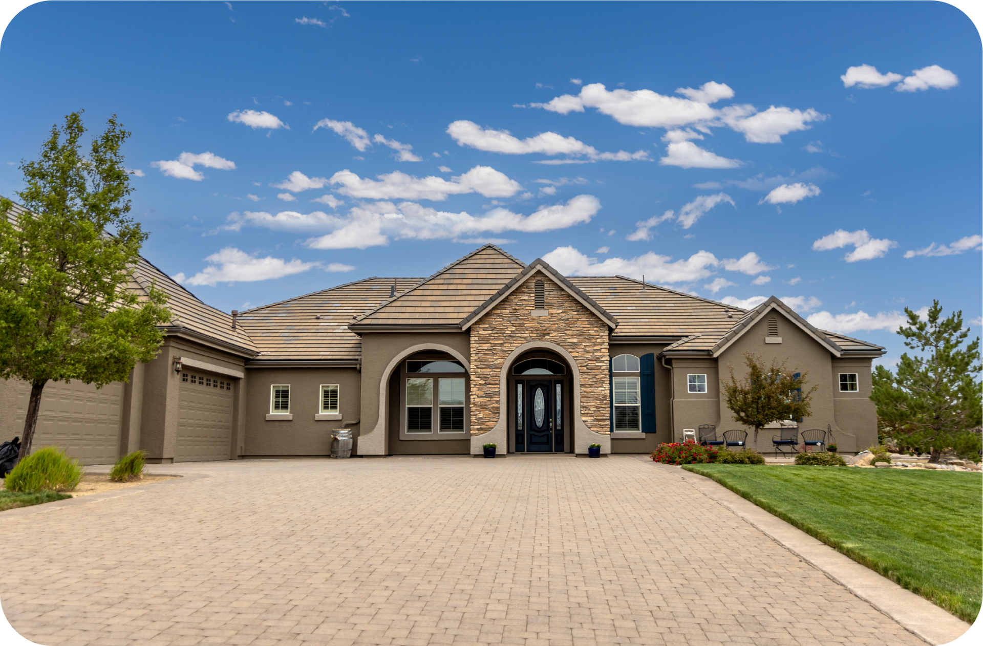 A large house with a brick driveway and a blue sky in the background.