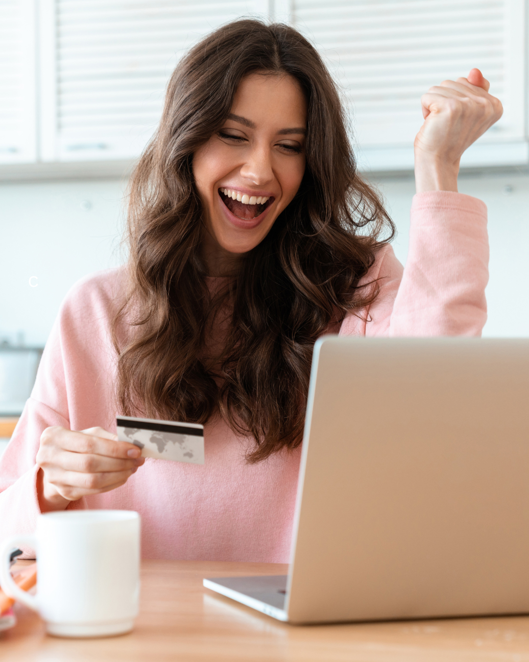 A woman is holding a credit card and using a laptop computer.