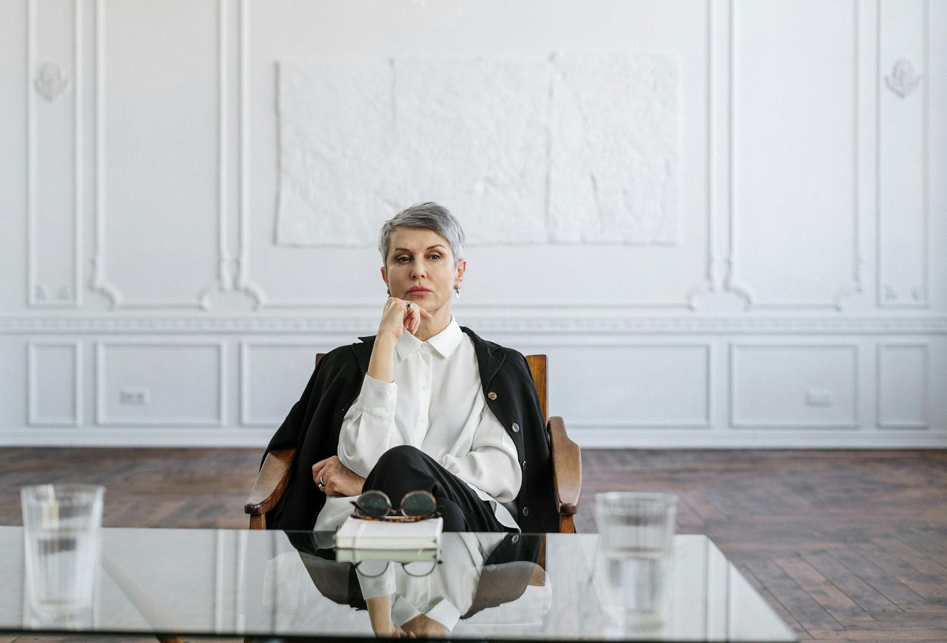 A woman is sitting at a table with her hand on her chin.