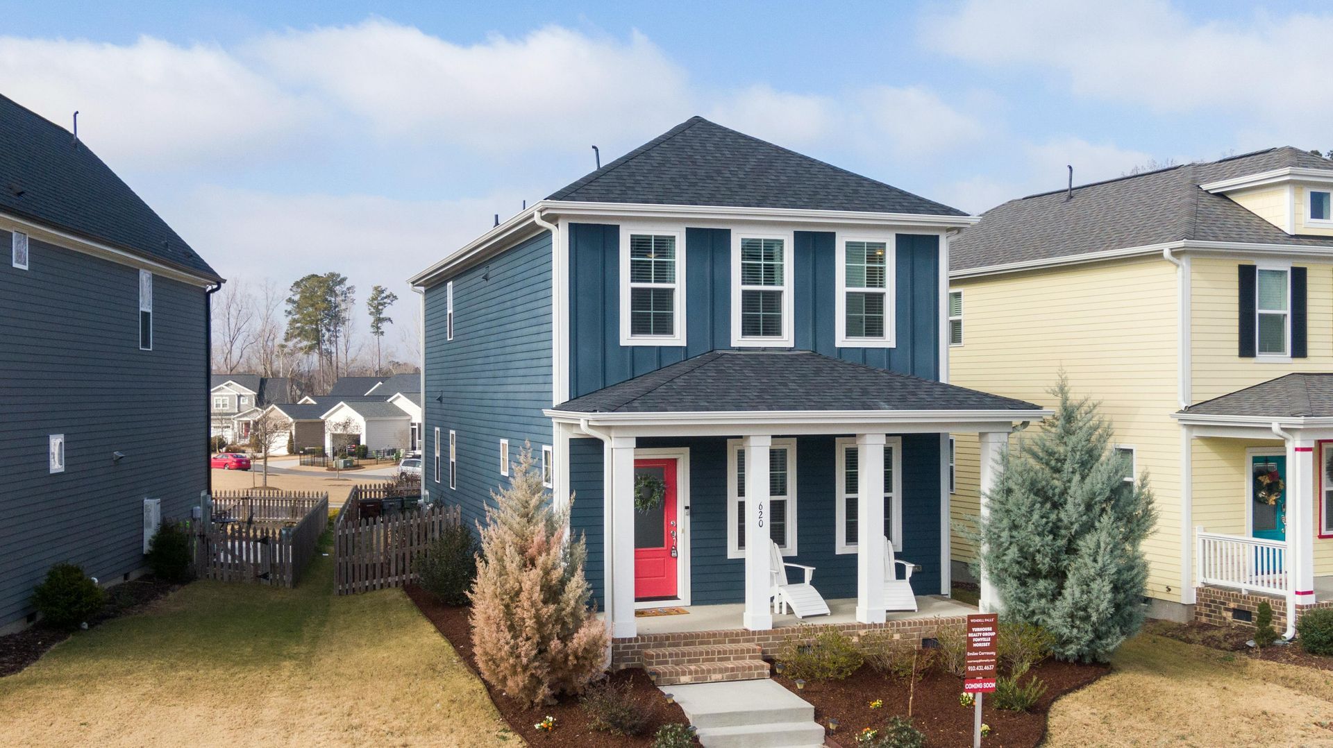 A blue house with a red door is surrounded by other houses.