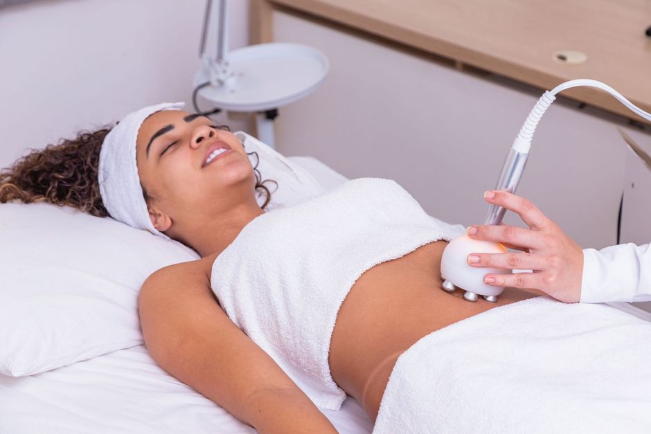 a woman is laying on a bed getting a treatment on her stomach