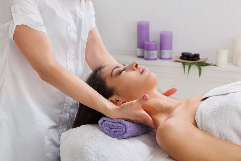 a woman is getting a massage with purple candles in the background
