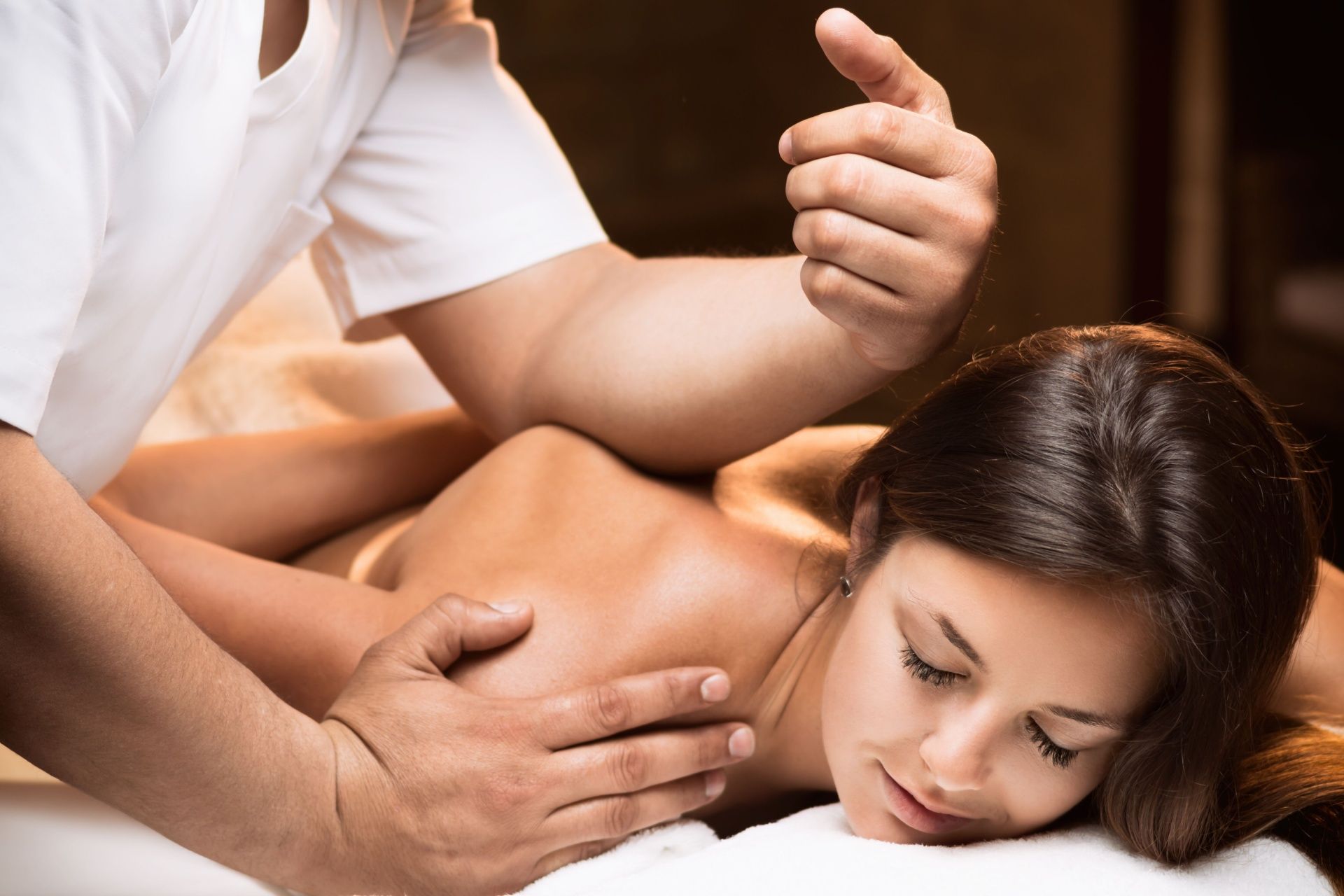 A woman is laying on a bed getting a massage from a man.