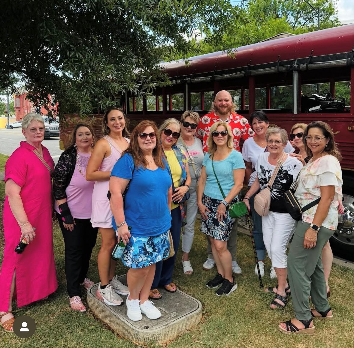 A group of people standing outside by a large red vehicle.