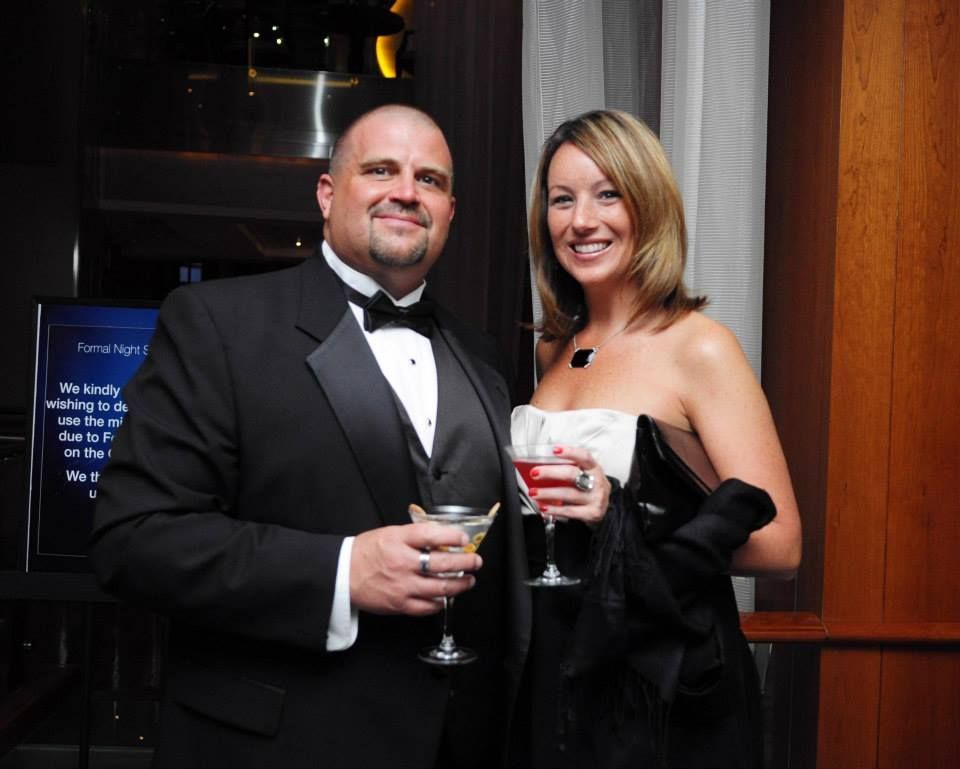 Woman in gray shirt and jeans, man in blue shirt and khakis, smiling, posing together.