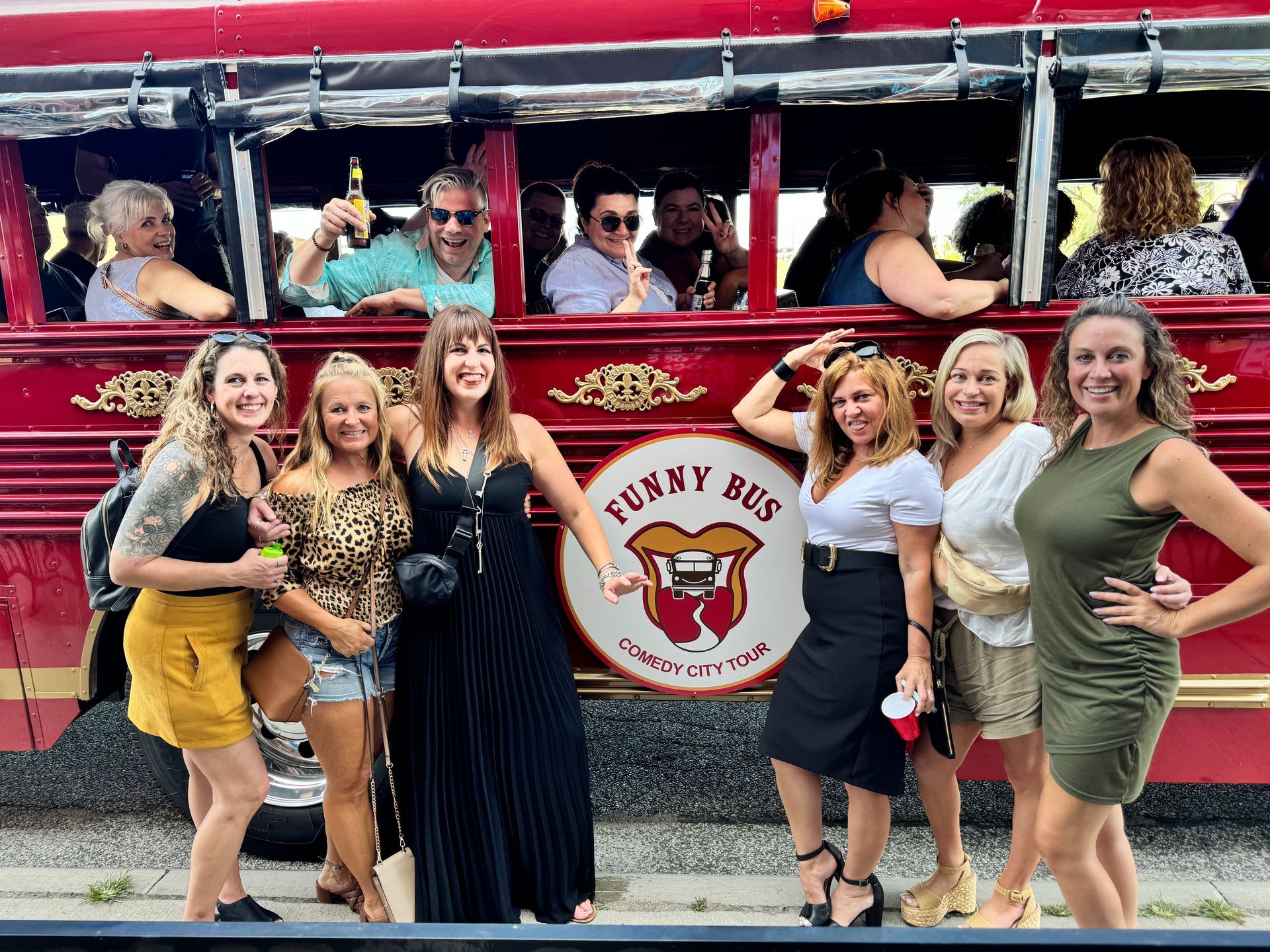 Group of people on a decorated trolley, smiling and wearing Christmas lights, ready to celebrate.