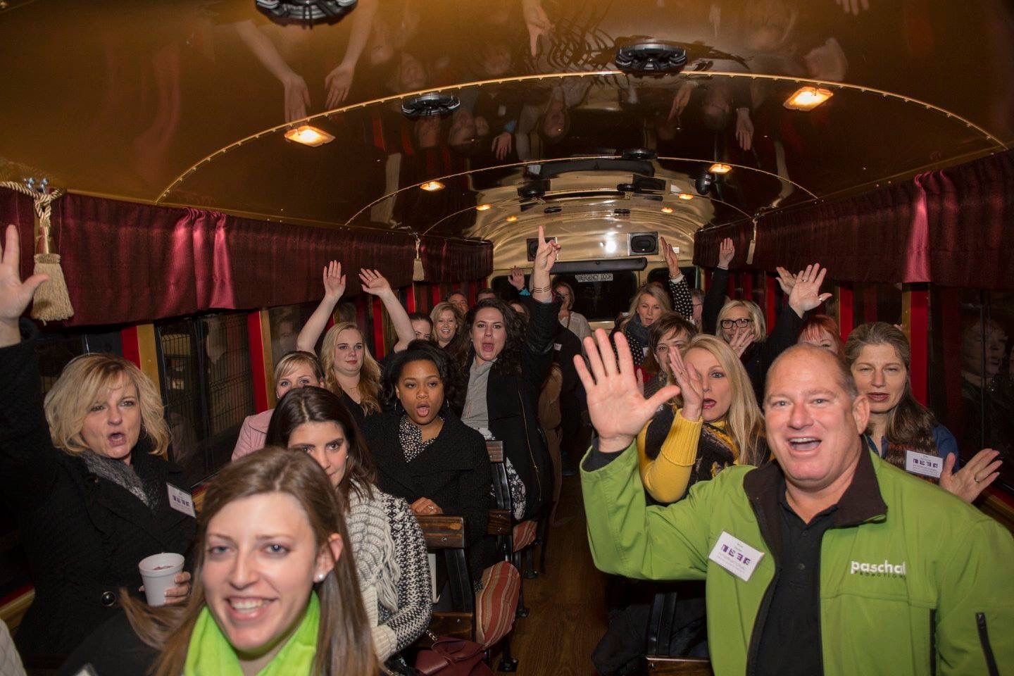 A group of people and a dog pose with a Grinch and a red bus decorated with Christmas lights.