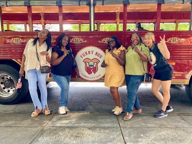 Five people pose smiling in front of a red 