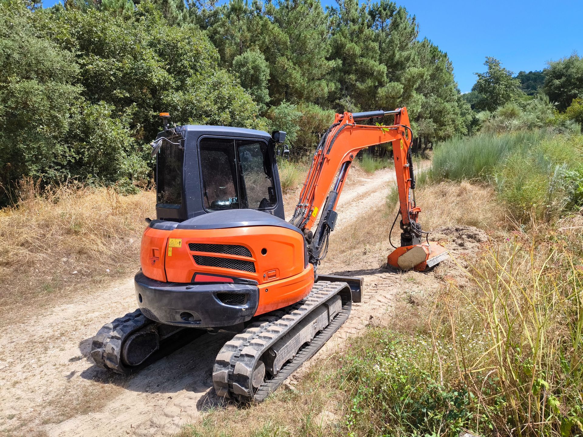 Mini excavator in action to efficiently clean the verges of a rural road