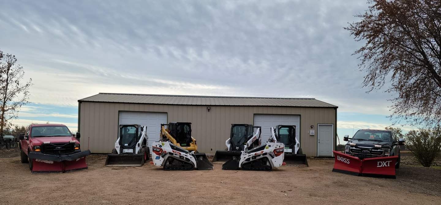 A row of snow plows are parked in front of a building.