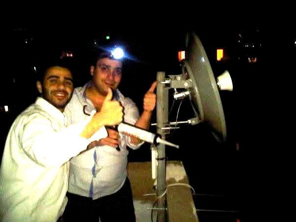 Fadi Helou and team installing a long-range wireless bridge on a rooftop in Beirut, 2006 – early ISP infrastructure setup at night.