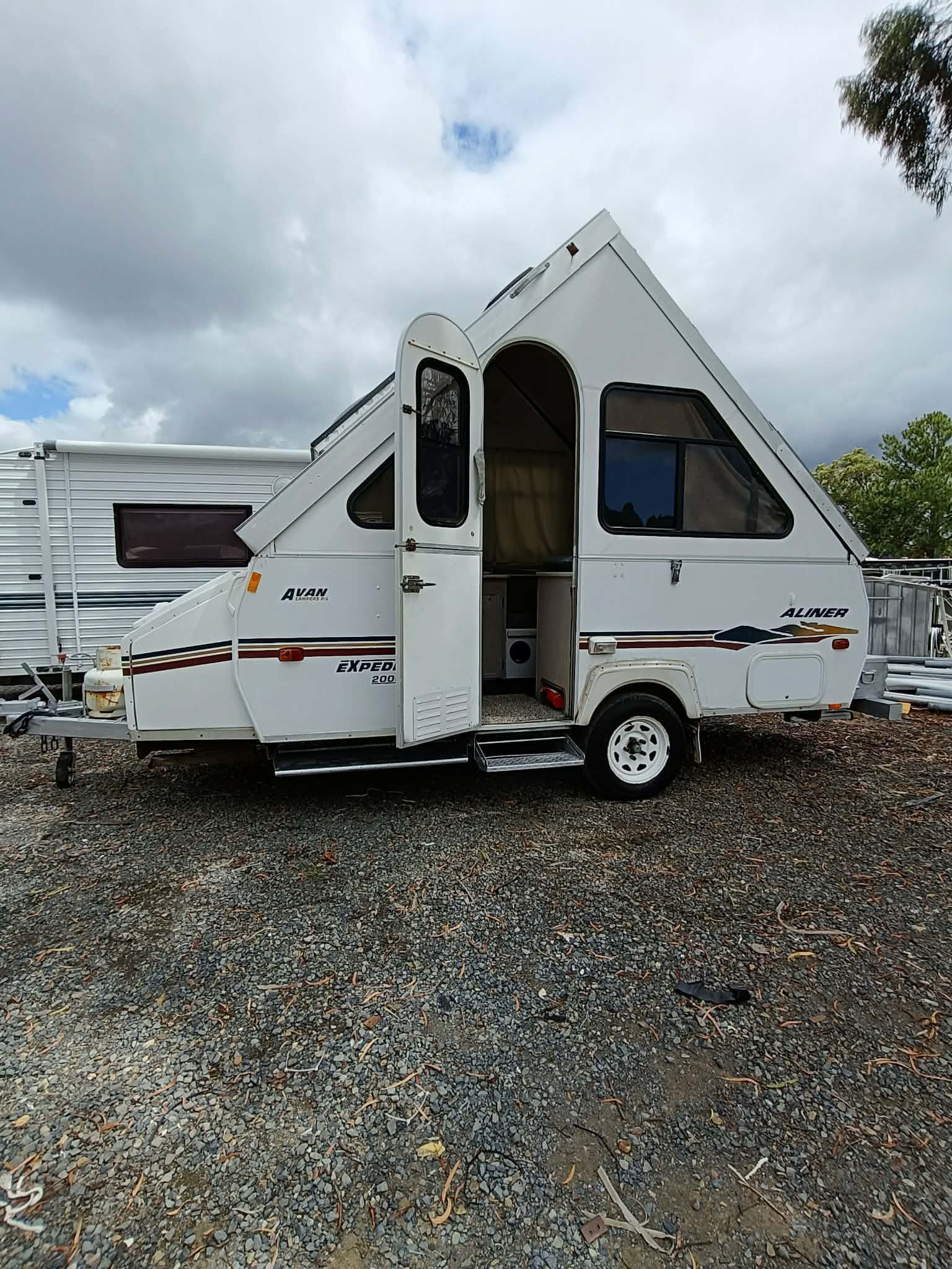 White a-frame Camper Trailer With an Open Door, Parked on Gravel — Great Lakes Caravans & RV P/L In Nabiac, NSW