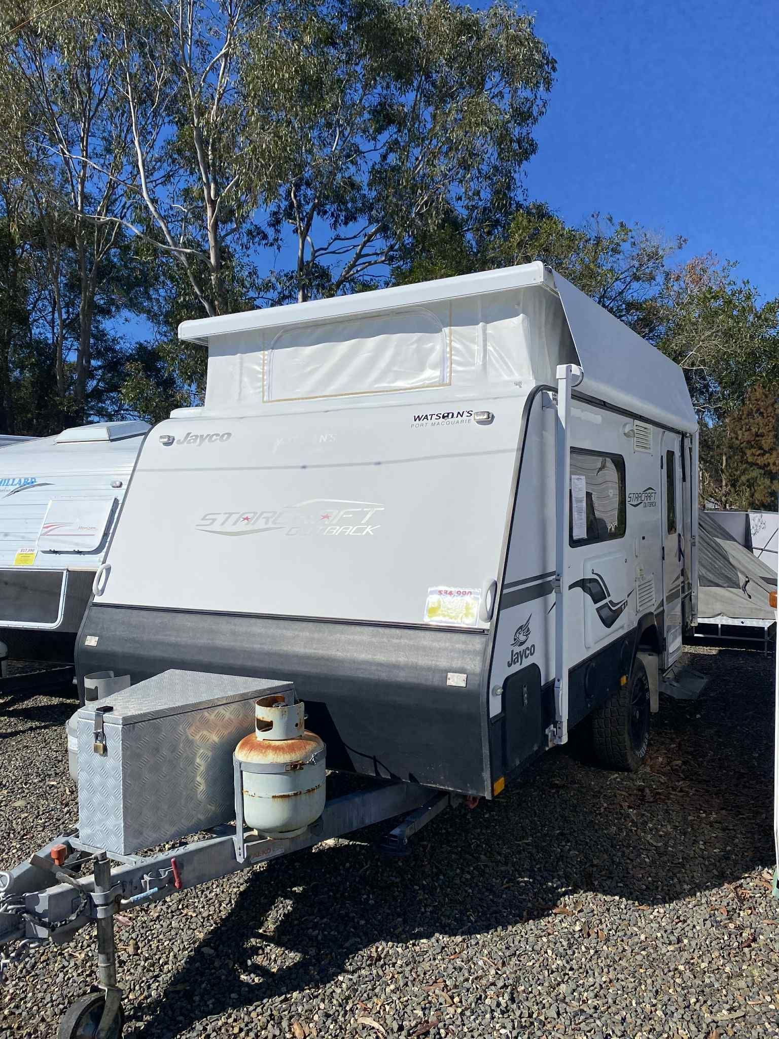 A Gray and White Pop-top Camper Trailer With an Open Door, Parked on Gravel — Great Lakes Caravans & RV P/L In Nabiac, NSW