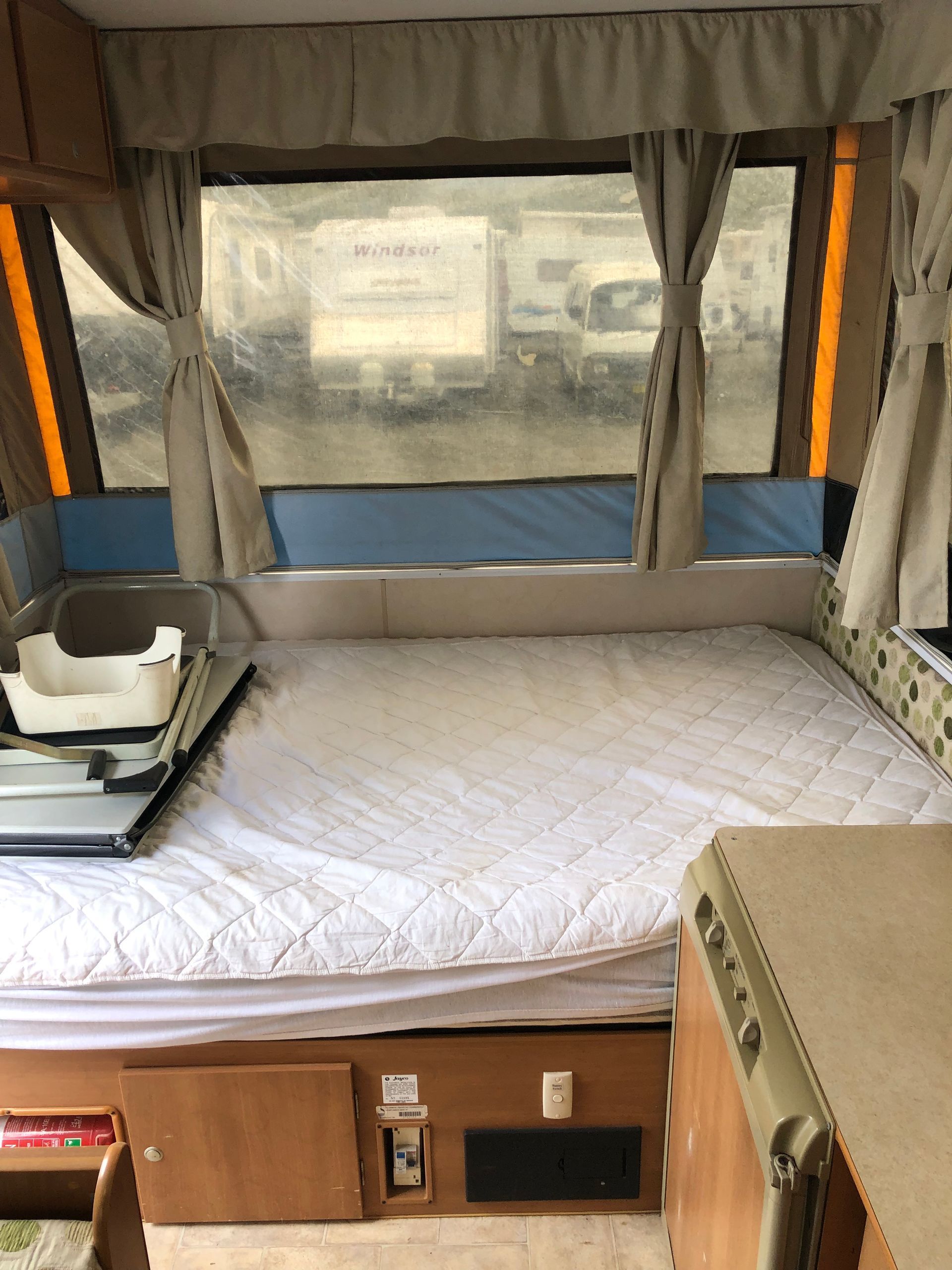 Interior of a Pop-up Camper With Bed, Window, and Small Kitchen Area — Great Lakes Caravans & RV P/L In Nabiac, NSW