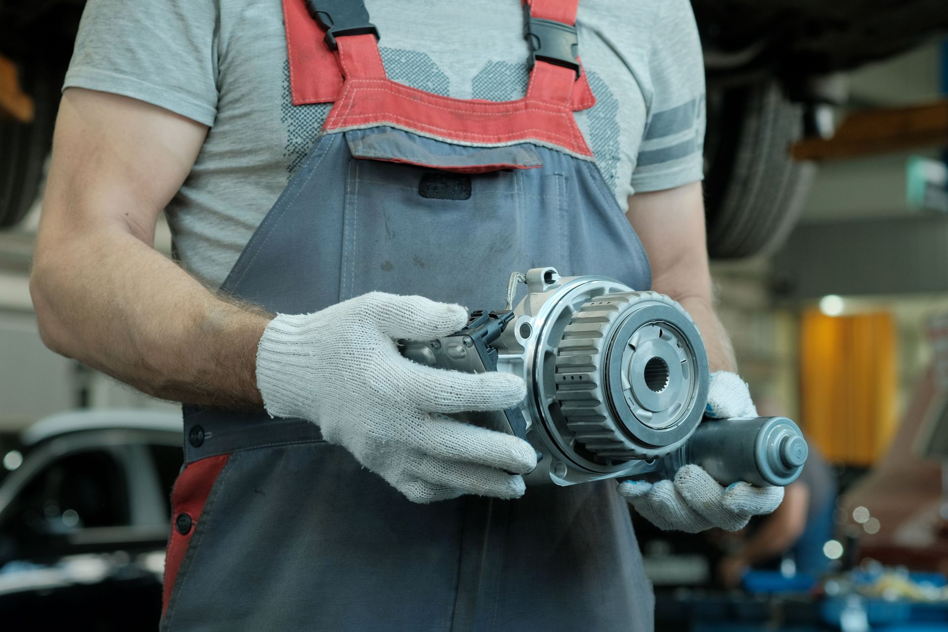 A mechanic's hands are holding a gearbox to perform an auto transmission replacement service.
