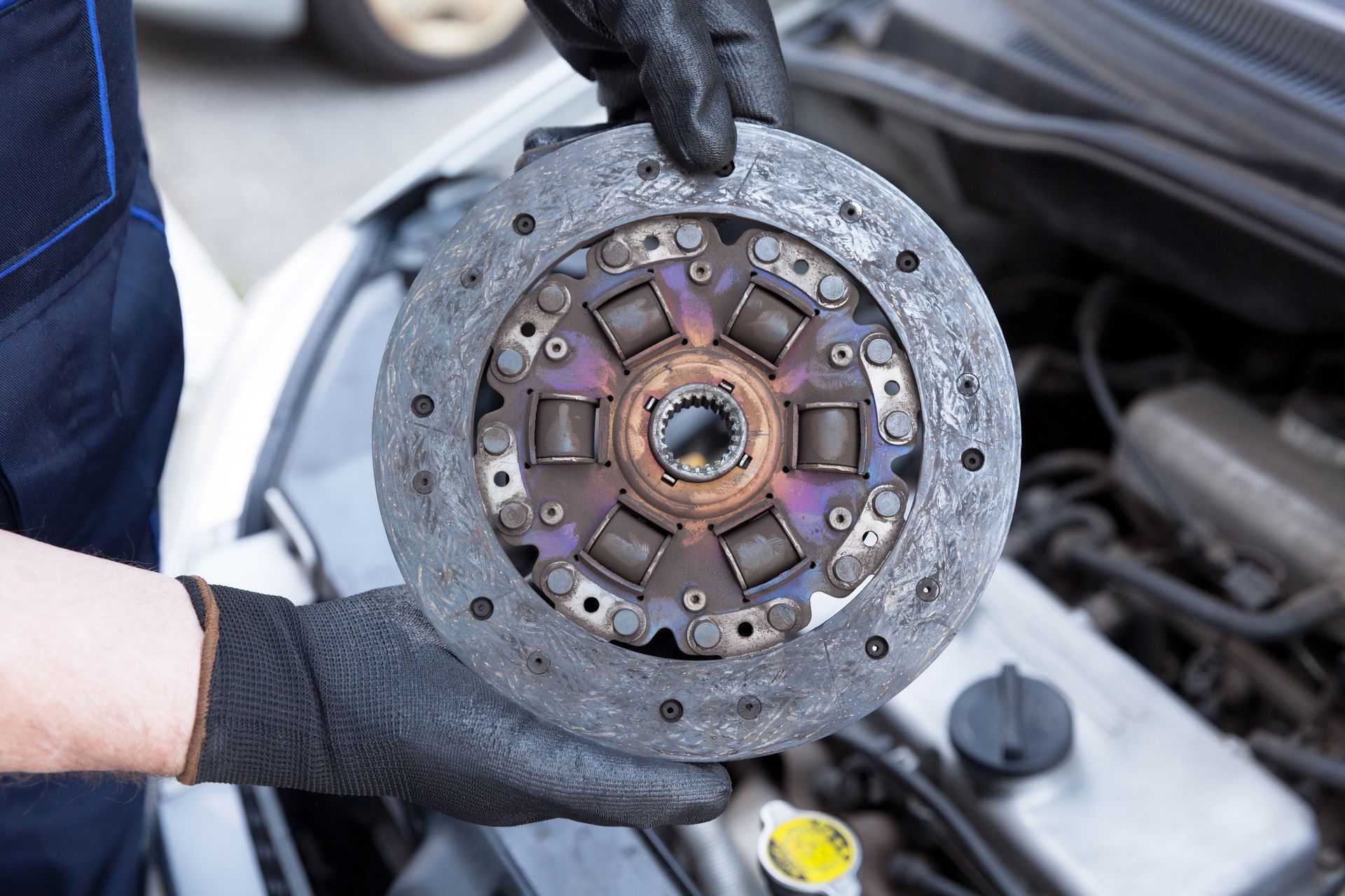 A Mechanic Wearing Protective Work Gloves Holds Old Clutch Discover a Car Engine | Canberra, Act | Auto Drive Transmission