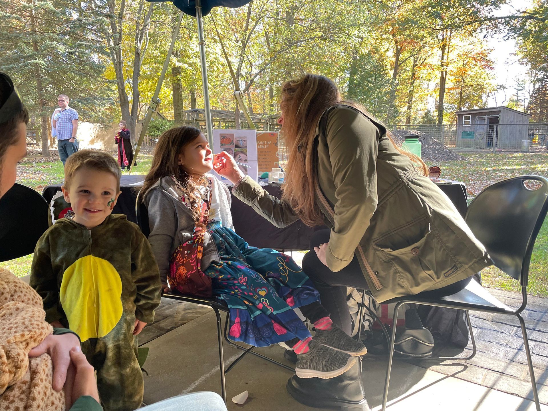 A small child gets her face painted by a volunteer at Spooky Safari.