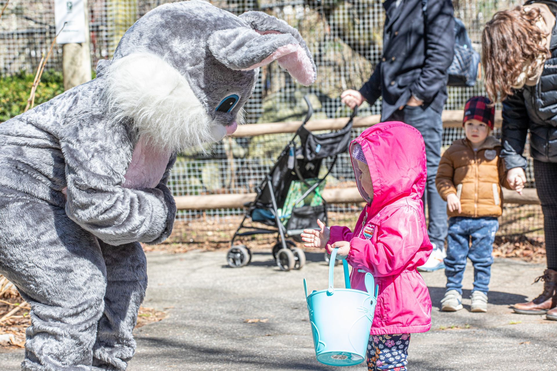 The Easter Bunny bends down to greet a child with an Easter basket.