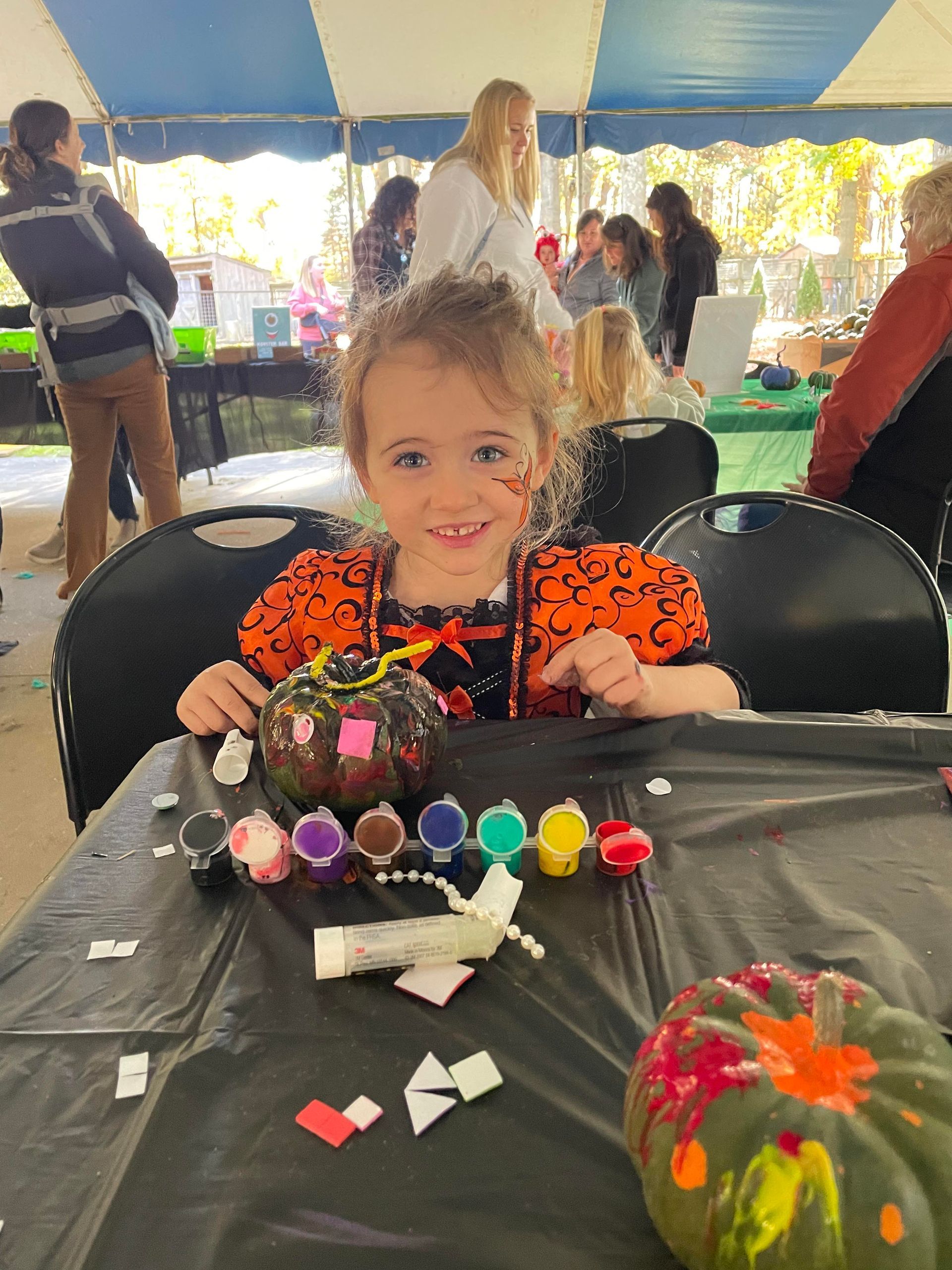 A child dressed as a Halloween princess paints a pumpkin at Spooky Safari.