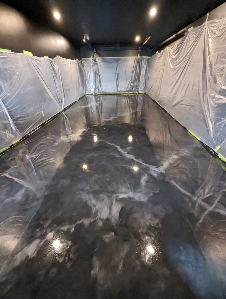 Une longue pièce avec un sol noir et un plafond recouvert de plastique.