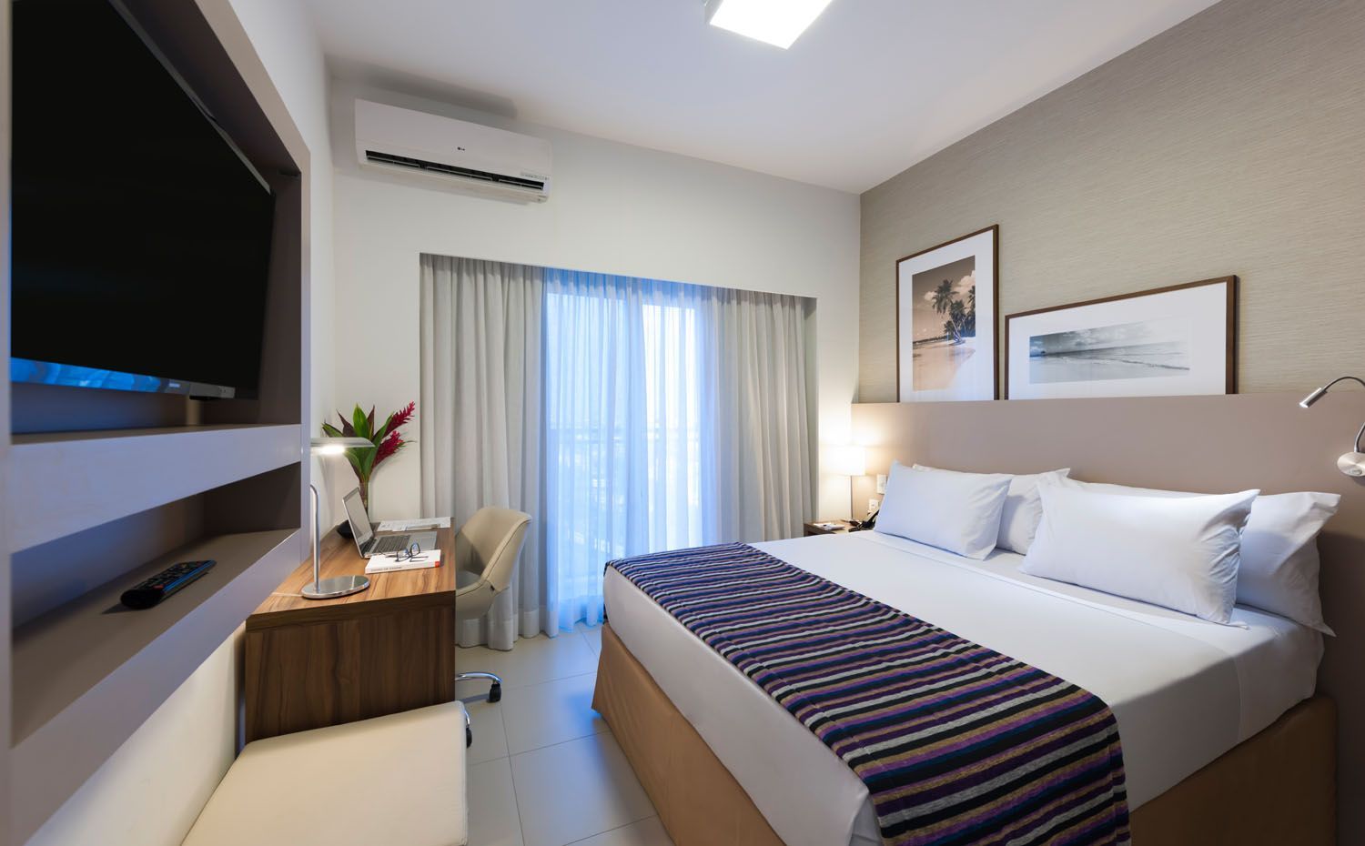 Um quarto de hotel com uma cama king size e uma TV de tela plana